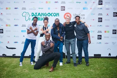 Attendees striking a pose at the DjangoCon Africa 2025 sponsor wall